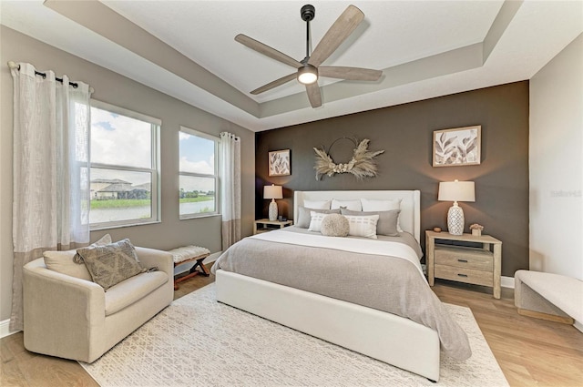 17898 Cherished Loop, Bradenton, FL 34211 - bedroom featuring a tray ceiling, light wood-style floors, baseboards, and ceiling fan