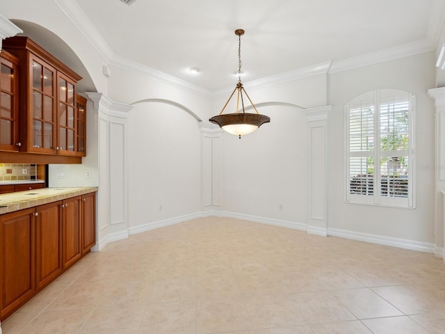6811 Honeysuckle Trl, Lakewood Ranch, FL 34202 - unfurnished dining area featuring decorative columns, light tile patterned flooring, crown molding, and arched walkways