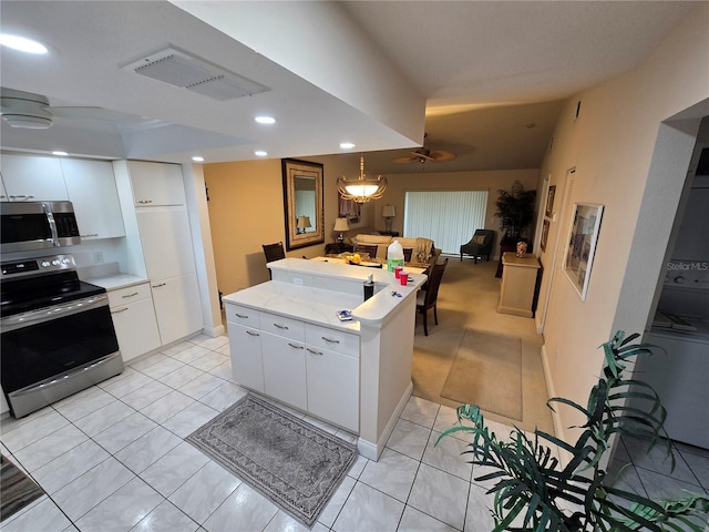 1211 Capri Isles Blvd Unit 116, Venice, FL 34292 - kitchen featuring stainless steel appliances, white cabinets, light countertops, a kitchen island, and recessed lighting