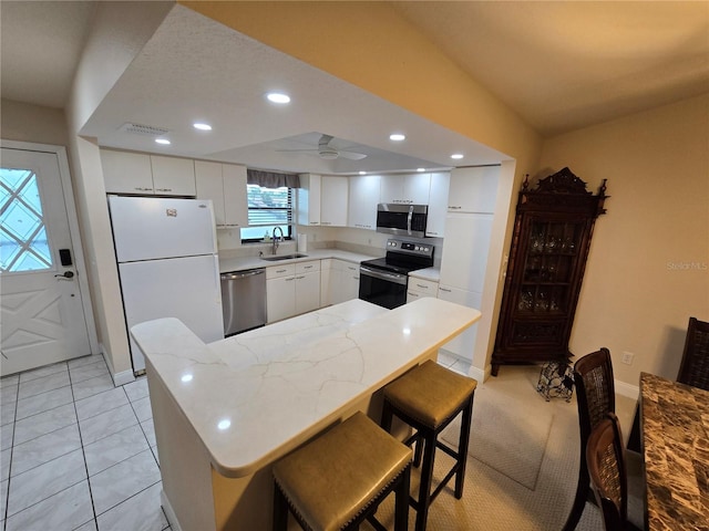 1211 Capri Isles Blvd Unit 116, Venice, FL 34292 - kitchen with stainless steel appliances, a sink, white cabinets, baseboards, and recessed lighting