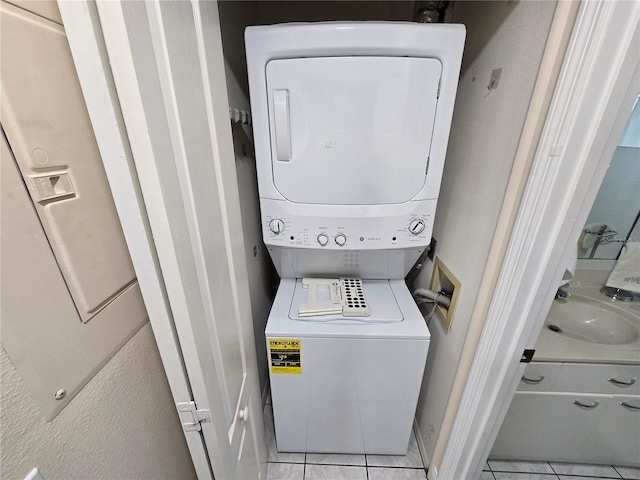 1211 Capri Isles Blvd Unit 116, Venice, FL 34292 - washroom featuring stacked washing machine and dryer, light tile patterned floors, and baseboards
