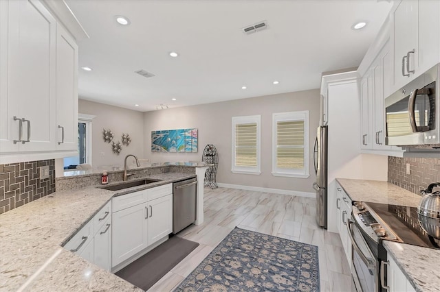 5142 51st Ln W, Bradenton, FL 34210 - kitchen with appliances with stainless steel finishes, white cabinetry, recessed lighting, backsplash, and light stone countertops