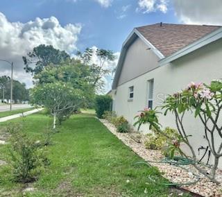 4811 14th Ave E, Bradenton, FL 34208 - view of side of property featuring a lawn, stucco siding, and a shingled roof