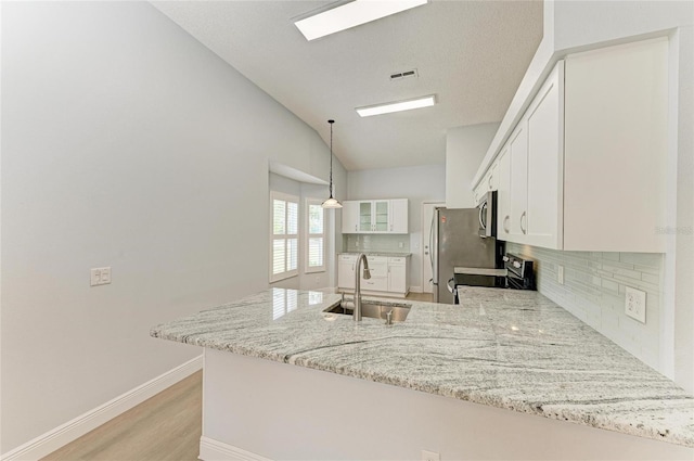 4811 14th Ave E, Bradenton, FL 34208 - kitchen with appliances with stainless steel finishes, tasteful backsplash, a peninsula, white cabinetry, and light stone countertops