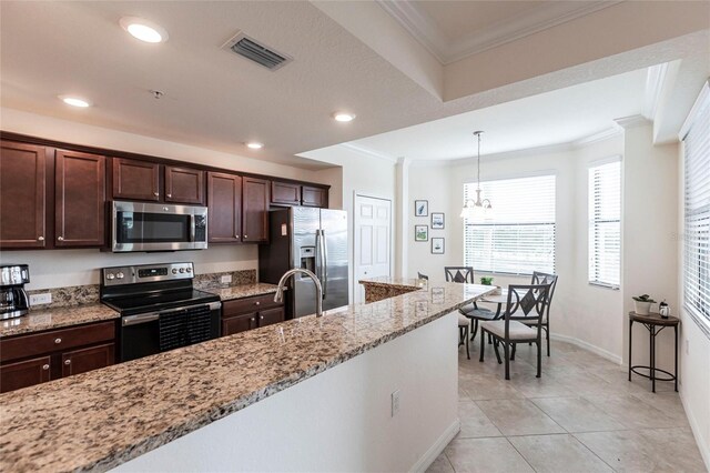 16804 Vardon Ter Unit 307, Bradenton, FL 34211 - kitchen with appliances with stainless steel finishes, ornamental molding, dark brown cabinetry, hanging light fixtures, and light stone countertops