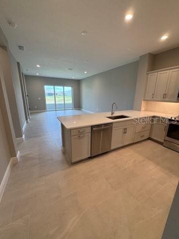 24827 Buckingham Way, Port Charlotte, FL 33980 - kitchen with appliances with stainless steel finishes, a sink, a peninsula, open floor plan, and light countertops