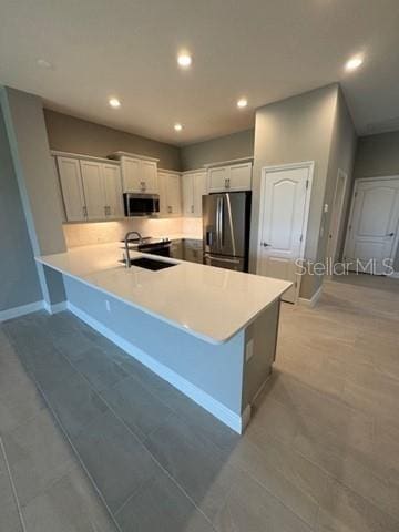 24827 Buckingham Way, Port Charlotte, FL 33980 - kitchen featuring appliances with stainless steel finishes, recessed lighting, a peninsula, baseboards, and white cabinetry
