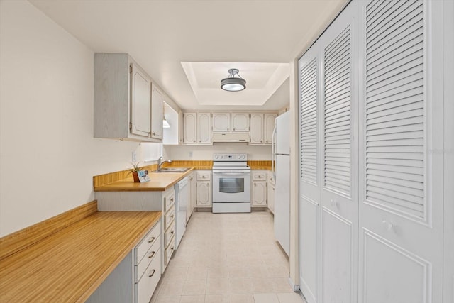 1227 56th St W Unit 1227, Bradenton, FL 34209 - kitchen with white appliances, under cabinet range hood, light countertops, a tray ceiling, and light tile patterned floors
