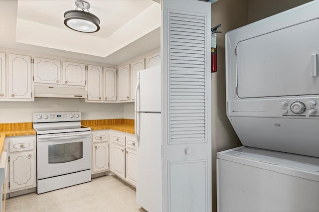 1227 56th St W Unit 1227, Bradenton, FL 34209 - kitchen featuring white appliances, stacked washer / drying machine, under cabinet range hood, light countertops, and a tray ceiling