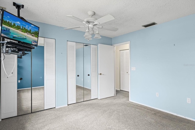 1227 56th St W Unit 1227, Bradenton, FL 34209 - unfurnished bedroom featuring multiple closets, carpet floors, a textured ceiling, and a ceiling fan