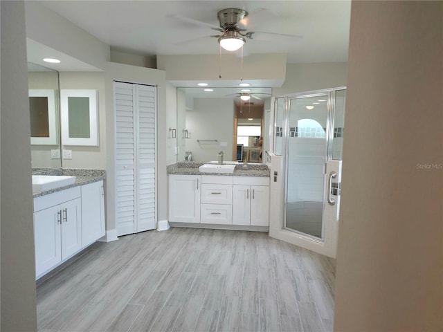 5207 86th Street Ct W, Bradenton, FL 34210 - bathroom with ceiling fan, two vanities, a shower stall, wood finished floors, and a closet