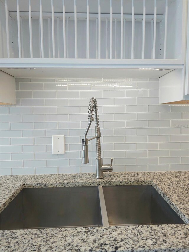 5207 86th Street Ct W, Bradenton, FL 34210 - kitchen view of backsplash, a sink, light stone countertops, and white cabinetry
