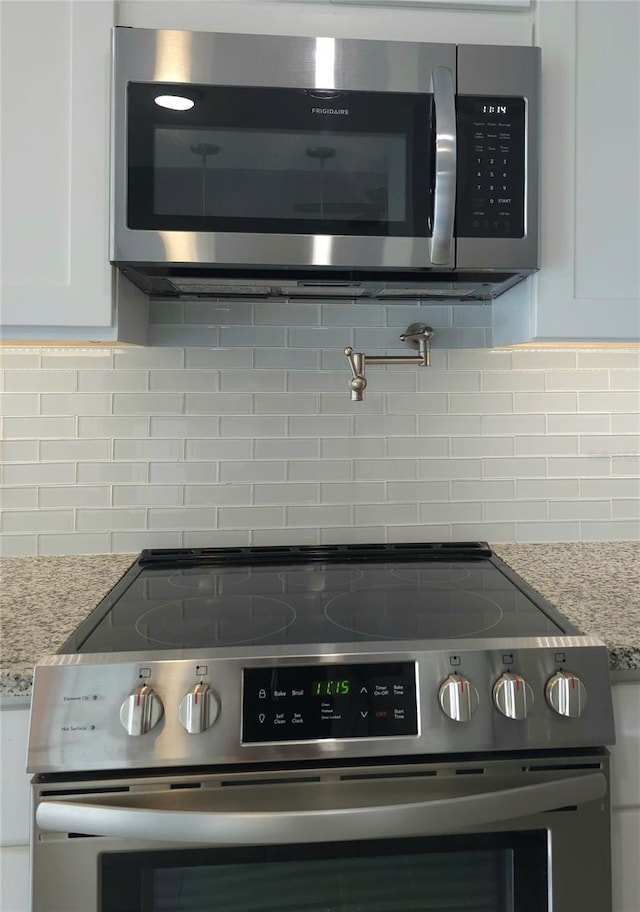 5207 86th Street Ct W, Bradenton, FL 34210 - kitchen view of appliances with stainless steel finishes, decorative backsplash, white cabinetry, and pot filler