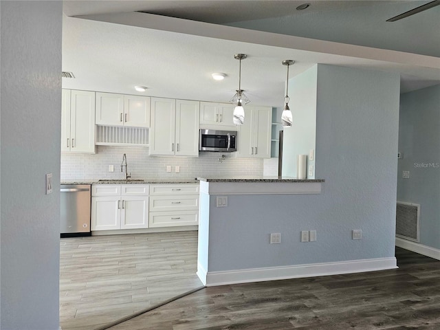 5207 86th Street Ct W, Bradenton, FL 34210 - kitchen featuring appliances with stainless steel finishes, a sink, light stone countertops, white cabinets, and light wood-style floors