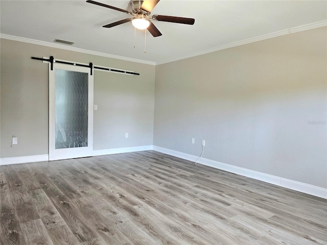 5207 86th Street Ct W, Bradenton, FL 34210 - empty room featuring a barn door, ornamental molding, baseboards, wood finished floors, and ceiling fan