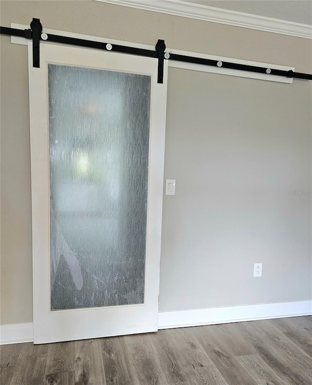 5207 86th Street Ct W, Bradenton, FL 34210 - detailed view of a barn door, wood finished floors, baseboards, and crown molding