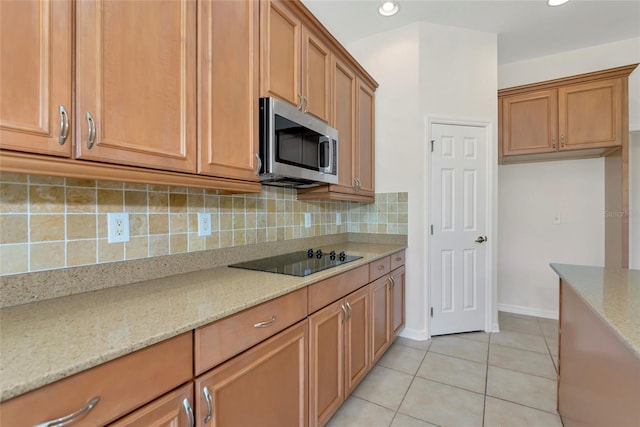 4307 70th Ave E, Ellenton, FL 34222 - kitchen with stainless steel microwave, black electric cooktop, light stone counters, decorative backsplash, and light tile patterned flooring