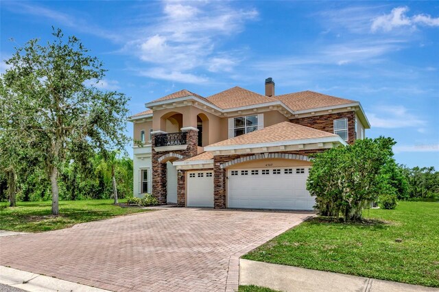 4307 70th Ave E, Ellenton, FL 34222 - view of front of home with a balcony, decorative driveway, stone siding, a front lawn, and a garage