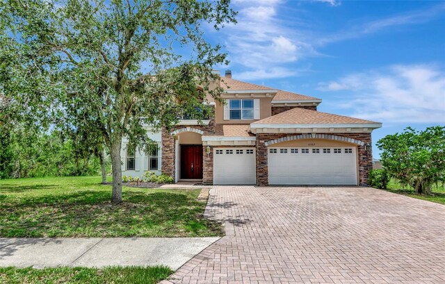 4307 70th Ave E, Ellenton, FL 34222 - view of front facade featuring decorative driveway, a front lawn, stone siding, an attached garage, and stucco siding