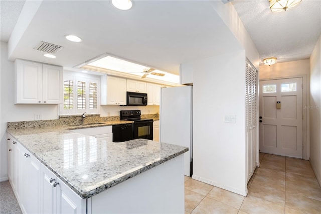 9412 Concord Cir, Bradenton, FL 34210 - kitchen featuring black appliances, a sink, a peninsula, light tile patterned floors, and white cabinetry