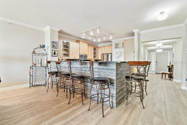 2825 Terra Ceia Bay Blvd Unit 1804, Palmetto, FL 34221 - kitchen with stainless steel appliances, light wood-type flooring, light brown cabinetry, a breakfast bar, and crown molding