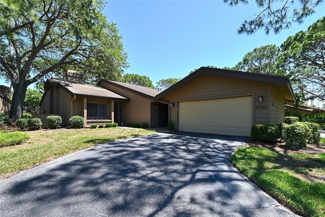 4555 Chandlers Forde Unit 47, Sarasota, FL 34235 - view of front of house featuring an attached garage, driveway, and a chimney