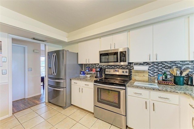 6804 19th Ave W, Bradenton, FL 34209 - kitchen with stainless steel appliances, light tile patterned flooring, tasteful backsplash, white cabinetry, and light stone counters