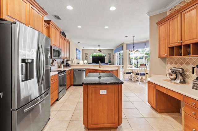 866 Oak Briar Ln, Osprey, FL 34229 - kitchen with stainless steel appliances, a peninsula, a center island, tasteful backsplash, and a desk