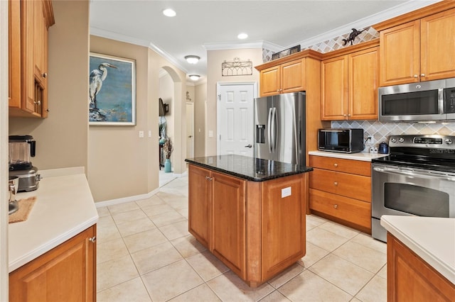 866 Oak Briar Ln, Osprey, FL 34229 - kitchen with appliances with stainless steel finishes, ornamental molding, arched walkways, a center island, and backsplash