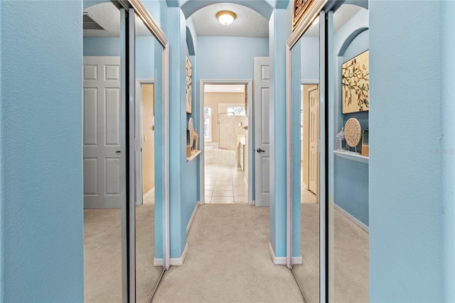 866 Oak Briar Ln, Osprey, FL 34229 - hallway with carpet flooring, arched walkways, baseboards, a textured ceiling, and a textured wall