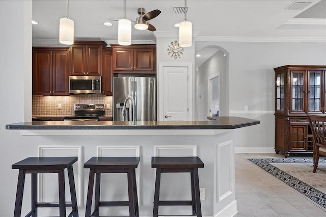 5117 Serata Dr, Bradenton, FL 34211 - kitchen featuring stainless steel appliances, dark countertops, a breakfast bar area, decorative backsplash, and crown molding