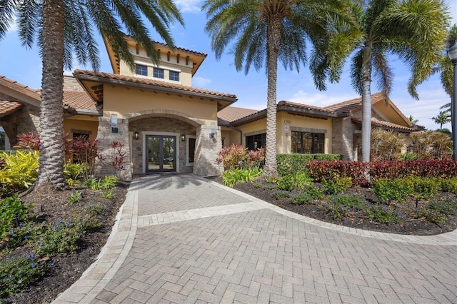 5117 Serata Dr, Bradenton, FL 34211 - view of front facade featuring french doors, stucco siding, stone siding, and a tiled roof