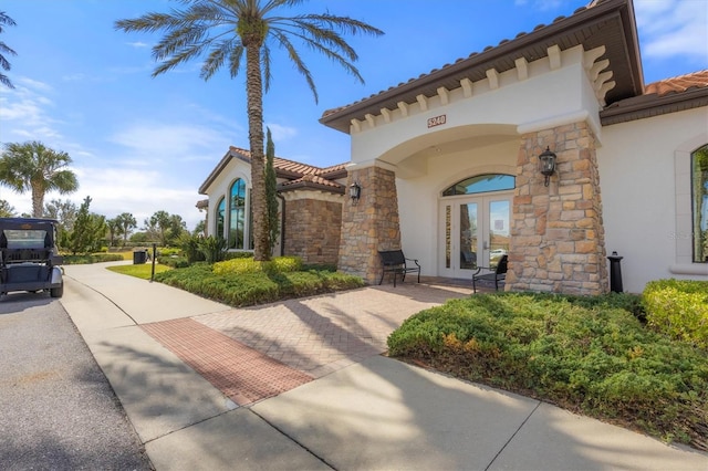 5117 Serata Dr, Bradenton, FL 34211 - view of front of home featuring french doors, stucco siding, a tiled roof, and stone siding