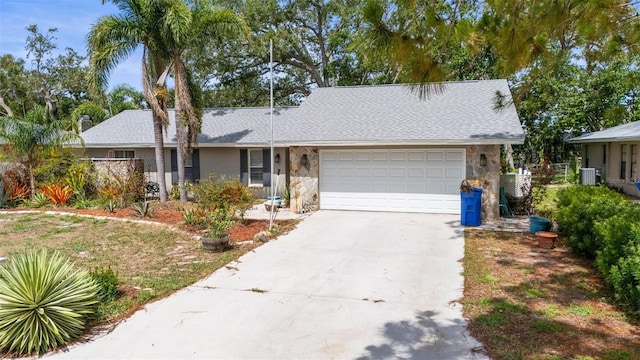 2204 67th St W, Bradenton, FL 34209 - view of front of home with stone siding, an attached garage, driveway, central AC unit, and roof with shingles