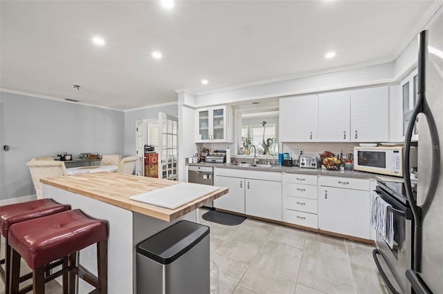 2204 67th St W, Bradenton, FL 34209 - kitchen with appliances with stainless steel finishes, a sink, ornamental molding, a kitchen bar, and white cabinets