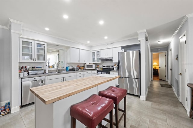 2204 67th St W, Bradenton, FL 34209 - kitchen with appliances with stainless steel finishes, wooden counters, crown molding, under cabinet range hood, and white cabinets