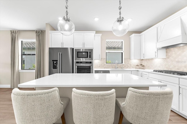 6791 Alstead Cir, Bradenton, FL 34202 - kitchen with stainless steel appliances, custom range hood, a center island, plenty of natural light, and recessed lighting