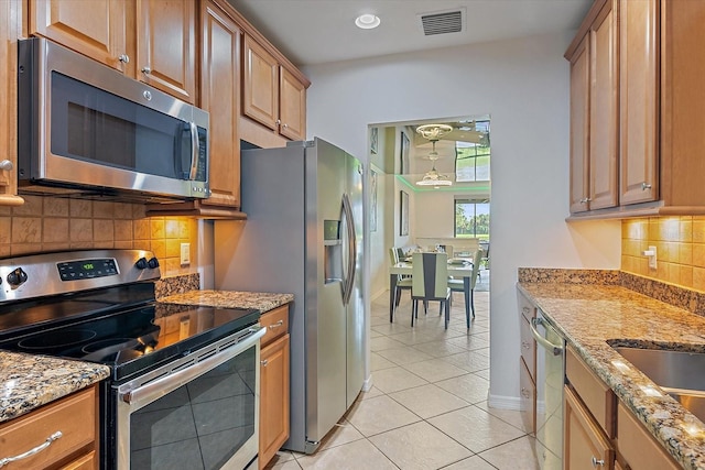 7325 Skybird Rd Unit 399, Bradenton, FL 34209 - kitchen featuring stainless steel appliances, light tile patterned floors, backsplash, light stone countertops, and baseboards
