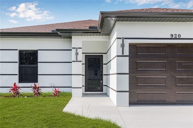 920 Barton St E, Lehigh Acres, FL 33974 - view of exterior entry with a lawn, a shingled roof, and stucco siding