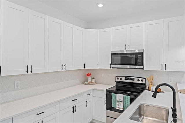 920 Barton St E, Lehigh Acres, FL 33974 - kitchen with appliances with stainless steel finishes, a sink, white cabinets, recessed lighting, and light stone counters