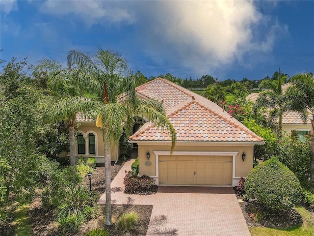 7542 Windy Hill Cv, Bradenton, FL 34202 - mediterranean / spanish home with decorative driveway, a garage, a tile roof, and stucco siding