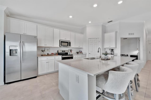 5695 Palmer Cir Unit 203, Bradenton, FL 34211 - kitchen featuring appliances with stainless steel finishes, ornamental molding, white cabinetry, a center island with sink, and a kitchen bar