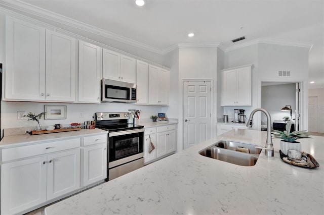 5695 Palmer Cir Unit 203, Bradenton, FL 34211 - kitchen with appliances with stainless steel finishes, white cabinets, ornamental molding, light stone counters, and recessed lighting