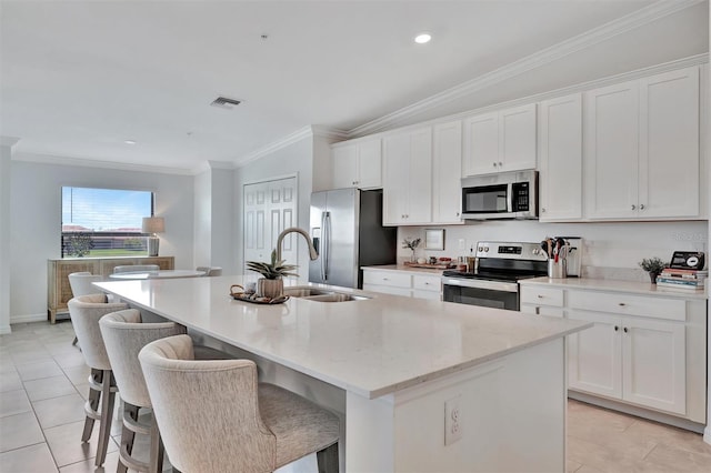 5695 Palmer Cir Unit 203, Bradenton, FL 34211 - kitchen featuring appliances with stainless steel finishes, an island with sink, light tile patterned floors, crown molding, and white cabinets