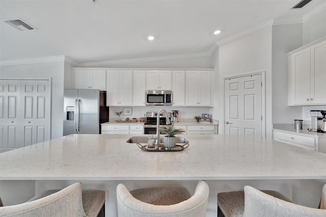 5695 Palmer Cir Unit 203, Bradenton, FL 34211 - kitchen featuring appliances with stainless steel finishes, white cabinets, a large island with sink, ornamental molding, and light stone countertops