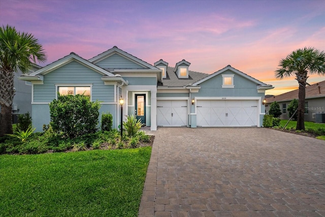 12139 Cranston Way, Bradenton, FL 34211 - view of front facade with decorative driveway, a garage, stucco siding, a front lawn, and central air condition unit