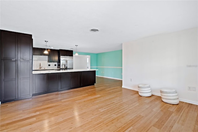 7355 Cass Cir, Sarasota, FL 34231 - kitchen with stainless steel fridge with ice dispenser, light countertops, light wood-type flooring, decorative light fixtures, and open floor plan