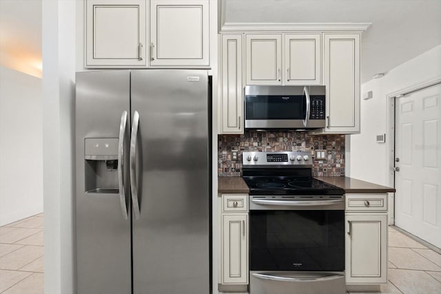 5433 81st Avenue Cir E, Palmetto, FL 34221 - kitchen featuring appliances with stainless steel finishes, dark countertops, light tile patterned floors, tasteful backsplash, and cream cabinetry