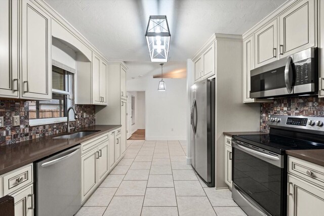 5433 81st Avenue Cir E, Palmetto, FL 34221 - kitchen with stainless steel appliances, a sink, dark countertops, decorative backsplash, and light tile patterned floors