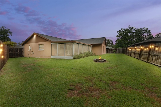 5433 81st Avenue Cir E, Palmetto, FL 34221 - back of property at dusk with a fire pit, stucco siding, and a sunroom